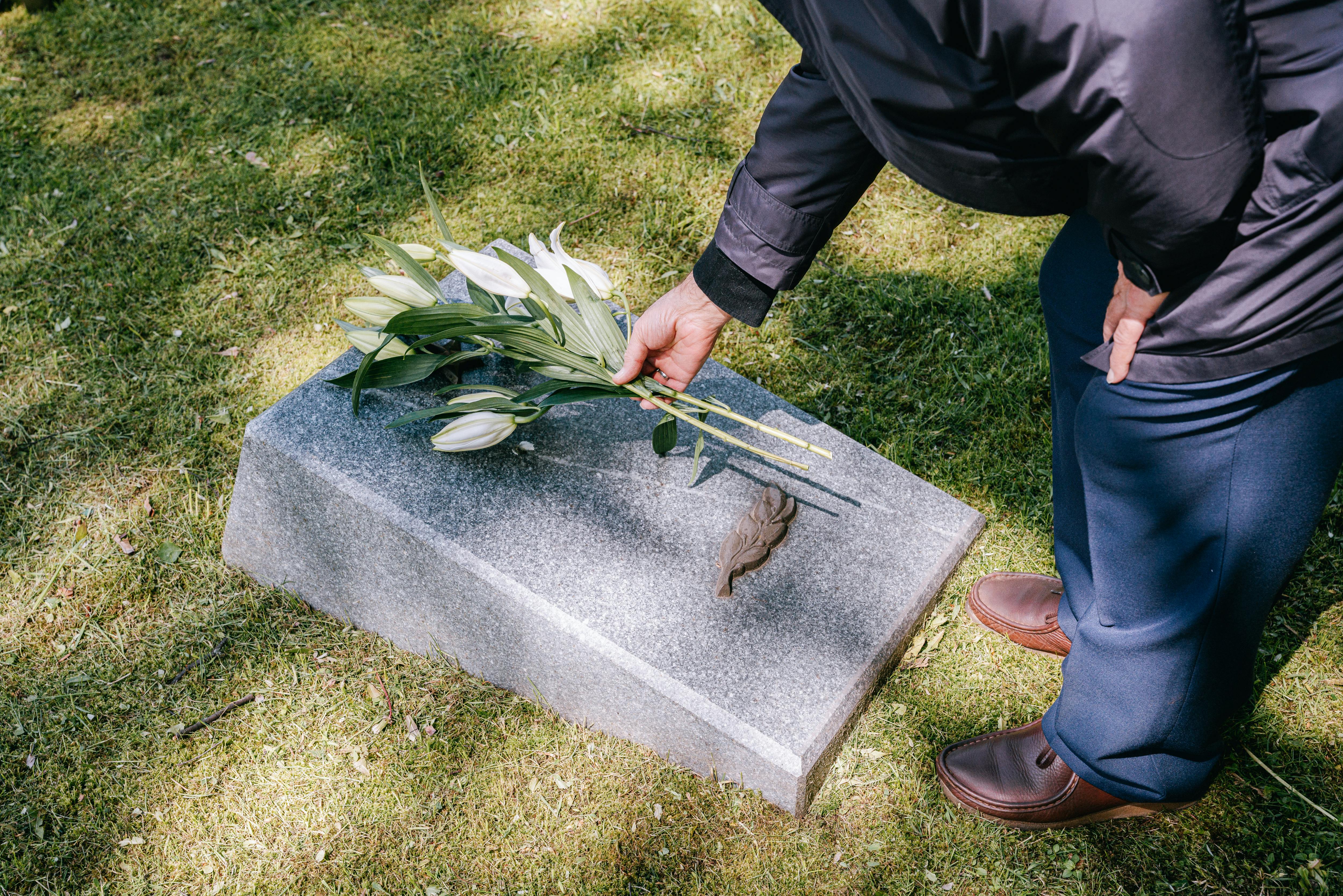 Homme déposant des fleurs sur une tombe